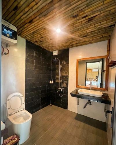 a bathroom with a toilet and a sink and a mirror at Chuồn Chuồn Resort Nghia Lo - Free Sauna & Onsen in Yên Bái