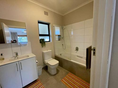 a bathroom with a toilet and a tub and a sink at Beach House on Pachena in Plettenberg Bay