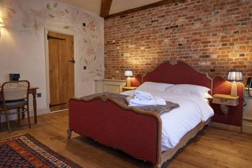 a bedroom with a large bed with a brick wall at The Dirty Habit in Hollingbourne