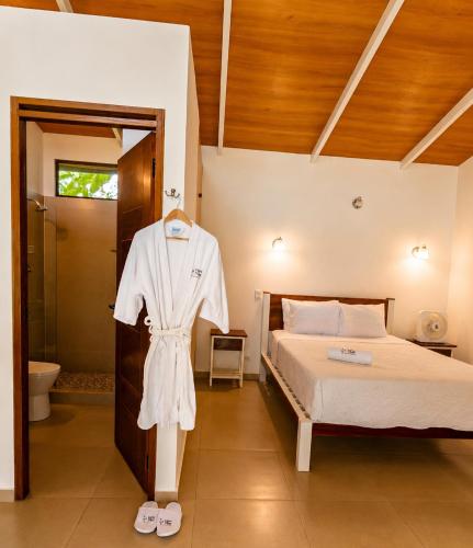 a bedroom with a bed and a robe on a rack at Lagoon Village B&B y SPA in Tarapoto