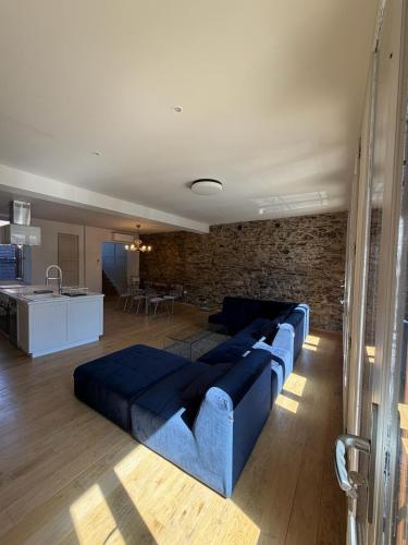 a living room with a blue couch and a kitchen at La myrtillette in Luchon