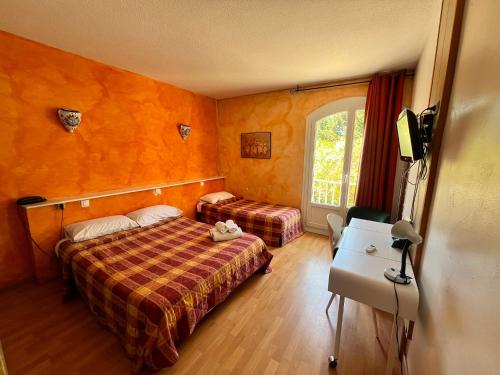 a bedroom with a bed and a desk and a window at Les Mimosas in Lunel