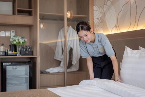 Eine Frau macht ein Bett in einem Hotelzimmer in der Unterkunft Thadatra INN in Phnom Penh
