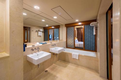 a bathroom with two sinks and a large mirror at Radisson Blu Dhaka Water Garden in Dhaka