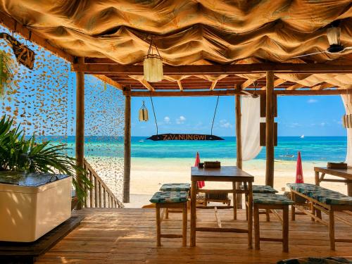 a wooden deck with a table and chairs on the beach at Zava Nungwi in Nungwi