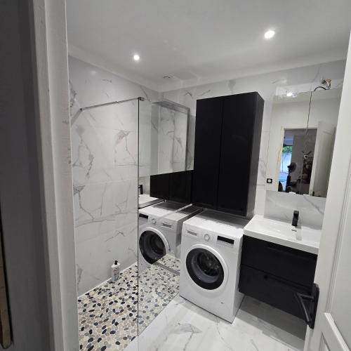 a white bathroom with a washing machine and a sink at Maison Lauret in Agde
