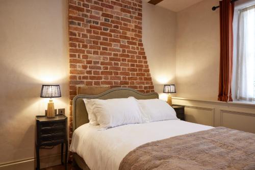 a bedroom with a bed with a brick wall at The Dirty Habit in Hollingbourne