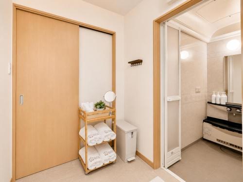 a bathroom with a closet with towels on a shelf at K2Guesthouse Konohana in Osaka