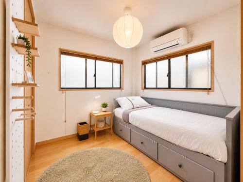a small bedroom with a bed and windows at K2Guesthouse Konohana in Osaka