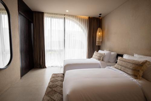 a hotel room with two beds and a window at SISI Wellness Villas in Bingin Beach