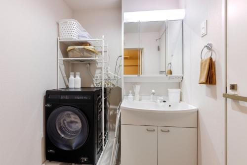 a bathroom with a washing machine next to a sink at Anecis名楽町 in Nagoya