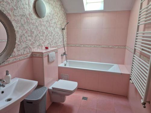 a pink bathroom with a tub and a toilet and a sink at Paradisul de la țara in Moara Vlăsiei