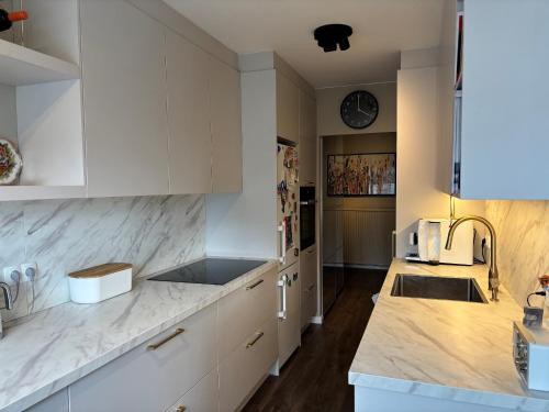 a kitchen with white cabinets and marble counter tops at Rofabær 45 in Reykjavík