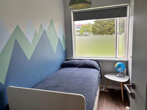a small bedroom with a bed and a window at Rofabær 45 in Reykjavík