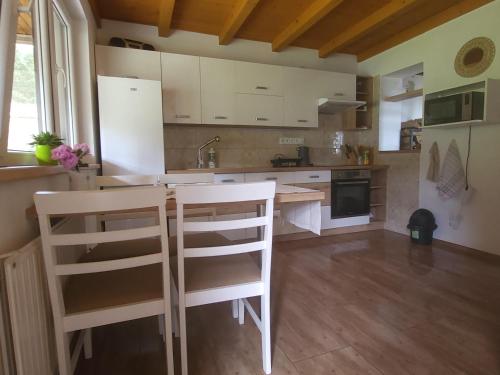 a kitchen with white cabinets and two white stools at Chata u lesa in Divec