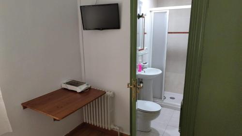 a bathroom with a toilet and a television on the wall at Hostal Restaurante Moderno in Cistierna