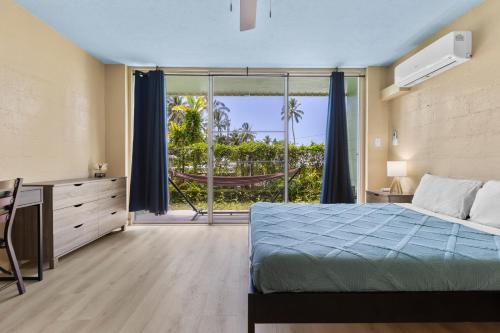 a bedroom with a bed and a desk and a window at Garden Balcony • Walk to Beach + Kitchen in Hilo