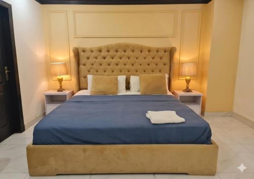 a bedroom with a large blue bed with two night stands at Zameen Opal Executive 2-Bed Suite in Lahore