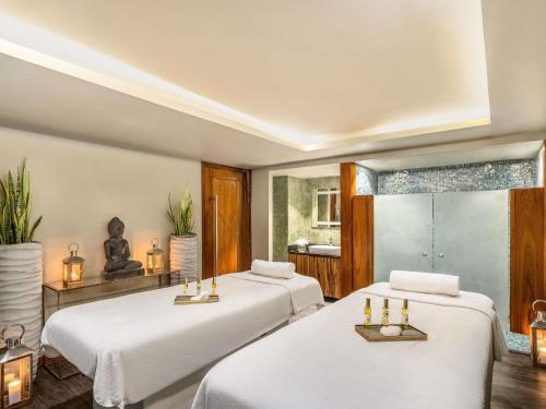 zwei Betten in einem Zimmer mit weißer Bettwäsche in der Unterkunft Pullman Abidjan in Abidjan