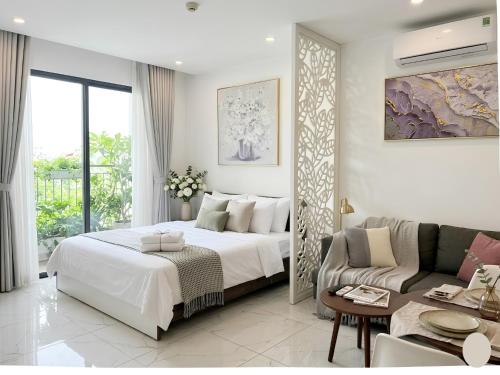 a white bedroom with a bed and a couch at Vinhomes D'capitale Hanoi Opus in Hanoi