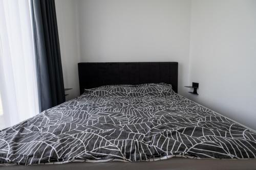 a bed with a black and white comforter at Sodyba Biruta in Tautrimai