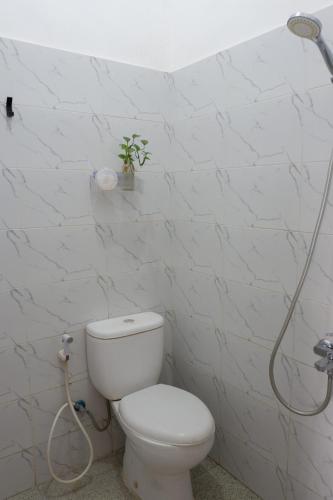 a white bathroom with a toilet and a shower at Kinari Sharia Living in Kediri