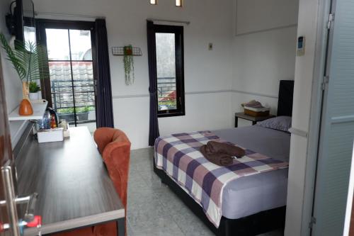 a bedroom with a bed and a desk and window at Kinari Sharia Living in Kediri