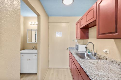 a kitchen with red cabinets and a sink at Garden Balcony • Walk to Beach + Kitchen in Hilo