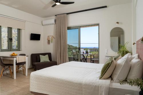 a bedroom with a large bed and a balcony at Kassiani Studios Olive Groove hotel in Plakias