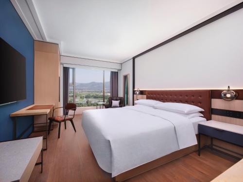 a bedroom with a large white bed and a desk at Four Points by Sheraton Shenzhen in Shenzhen