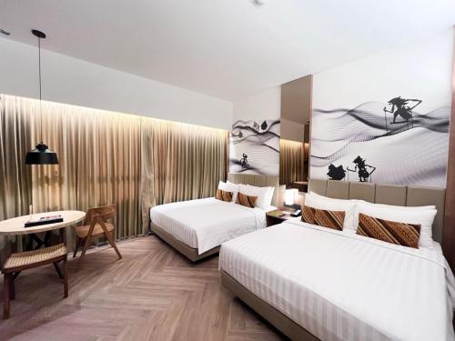 a hotel room with two beds and a table at Grand Zuri Malioboro in Yogyakarta