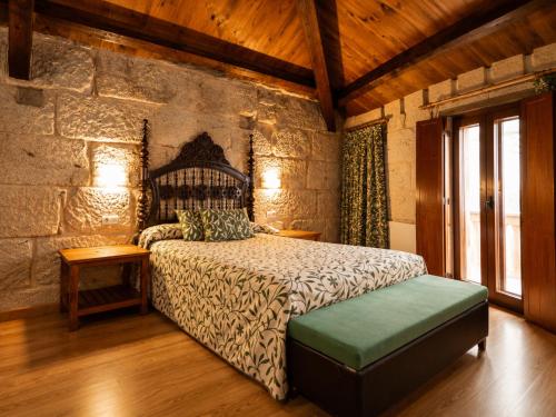 a bedroom with a bed and a stone wall at Hotel Boa Vila in Pontevedra