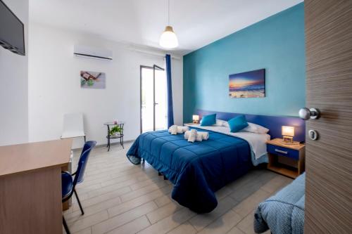 a blue bedroom with a bed and a desk at Giostemar Rooms - Playa Grande in Scicli