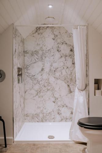 a bathroom with a shower with a marble wall at Caerketton Cabin in Kirknewton