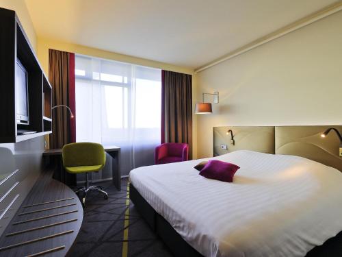 a hotel room with a bed with a purple pillow on it at Mercure Hotel Groningen Martiniplaza in Groningen