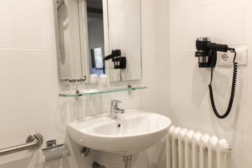 Baño blanco con lavabo y espejo en Hotel Nacional en La Jonquera