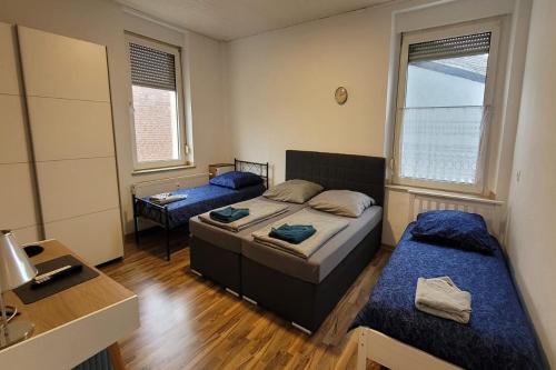 a bedroom with two beds and a desk and two windows at Privileg - NewTime in Viersen
