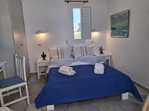 a bedroom with a blue bed with towels on it at kikis apartments in Drios