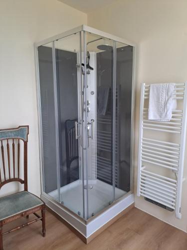 a glass shower stall in a room with a chair at Le pavillon des sœurs in Fontenille