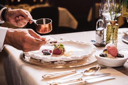 a person is serving a plate of food on a table at Hotel Jagdhaus Monzabon in Lech am Arlberg