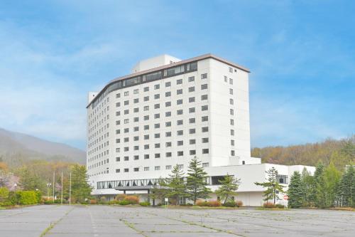 a large white building with a parking lot in front at Livemax Resort Hachimantai Forest in Hachimantai