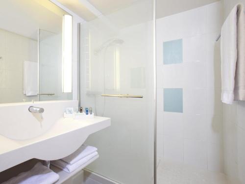 a white bathroom with a shower and a sink at Novotel Sheffield Centre in Sheffield