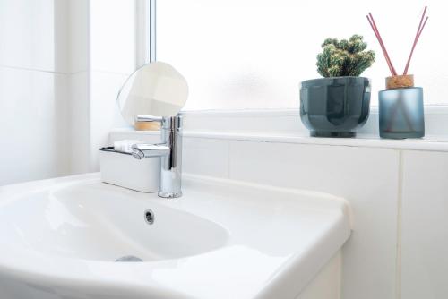 a white sink in a bathroom with a window at 4 Bed Contractor Apartment with Parking Central Banbury in Banbury