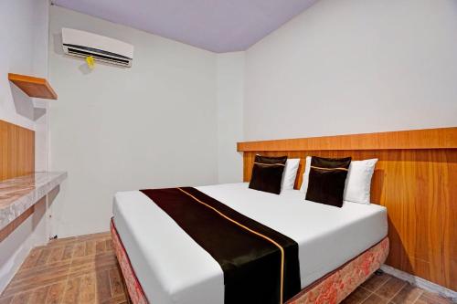a bedroom with a white bed with a wooden headboard at Collection O Bwalk Hotel Malang in Malang