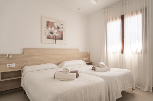 two beds in a white bedroom with towels on them at V110B Villa La Pau in Son Bou