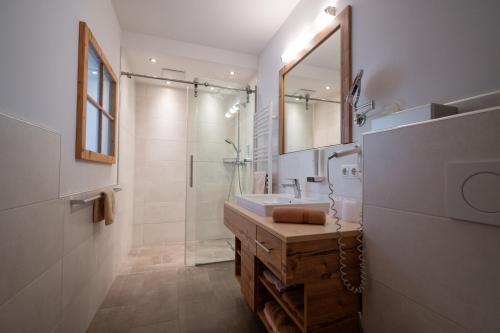 a bathroom with a sink and a shower with a mirror at Gasthof Bergblick in Berwang