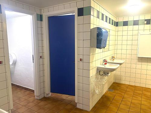 a bathroom with a blue door and a sink at Oasen Samsø in Nordby