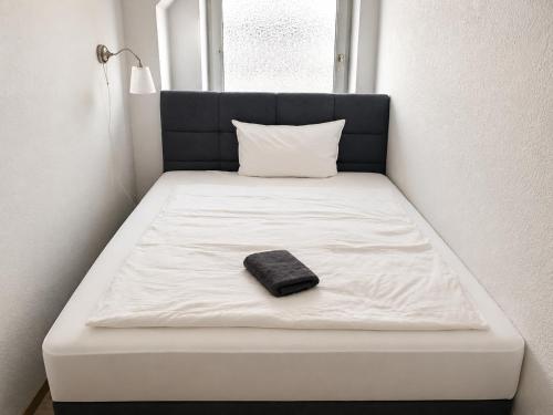 a white bed with a black pillow on it at NOBLE APART Saarbrücken City Center in Saarbrücken