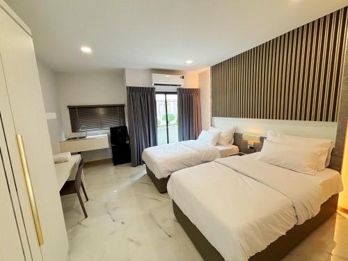 a hotel room with two beds and a desk at Jaroon House in Samutprakarn