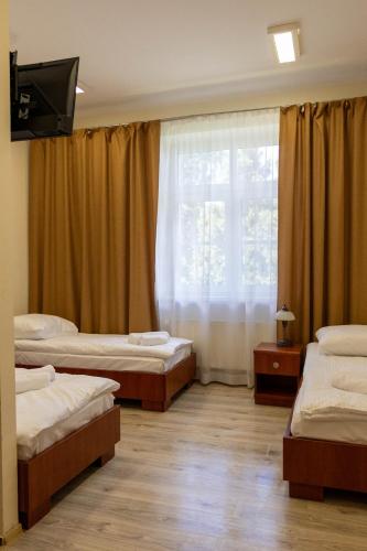 a room with three beds and a window at Kolegium Nowe PANS - hostel in Przemyśl